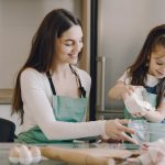 A joyful mother and daughter bonding while baking in the kitchen, smiling and enjoying the activity.