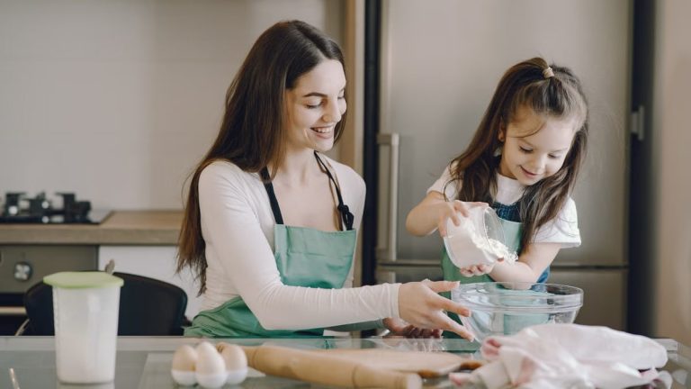 A joyful mother and daughter bonding while baking in the kitchen, smiling and enjoying the activity.